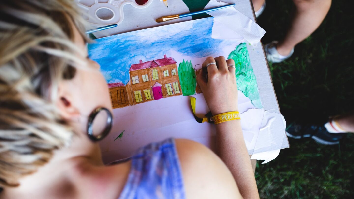 An overshoulder shot of a woman drawing a scene of Kelmarsh Hall