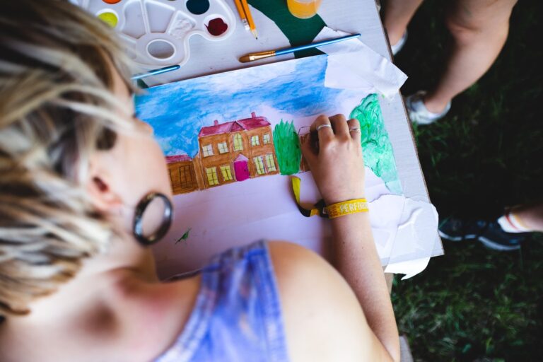 An overshoulder shot of a woman drawing a scene of Kelmarsh Hall