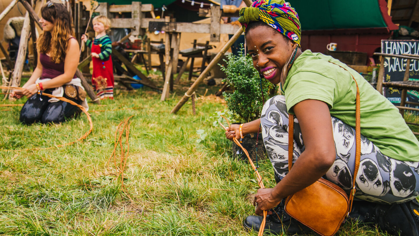 A woman with a headscarf smiles as she crafts with willow